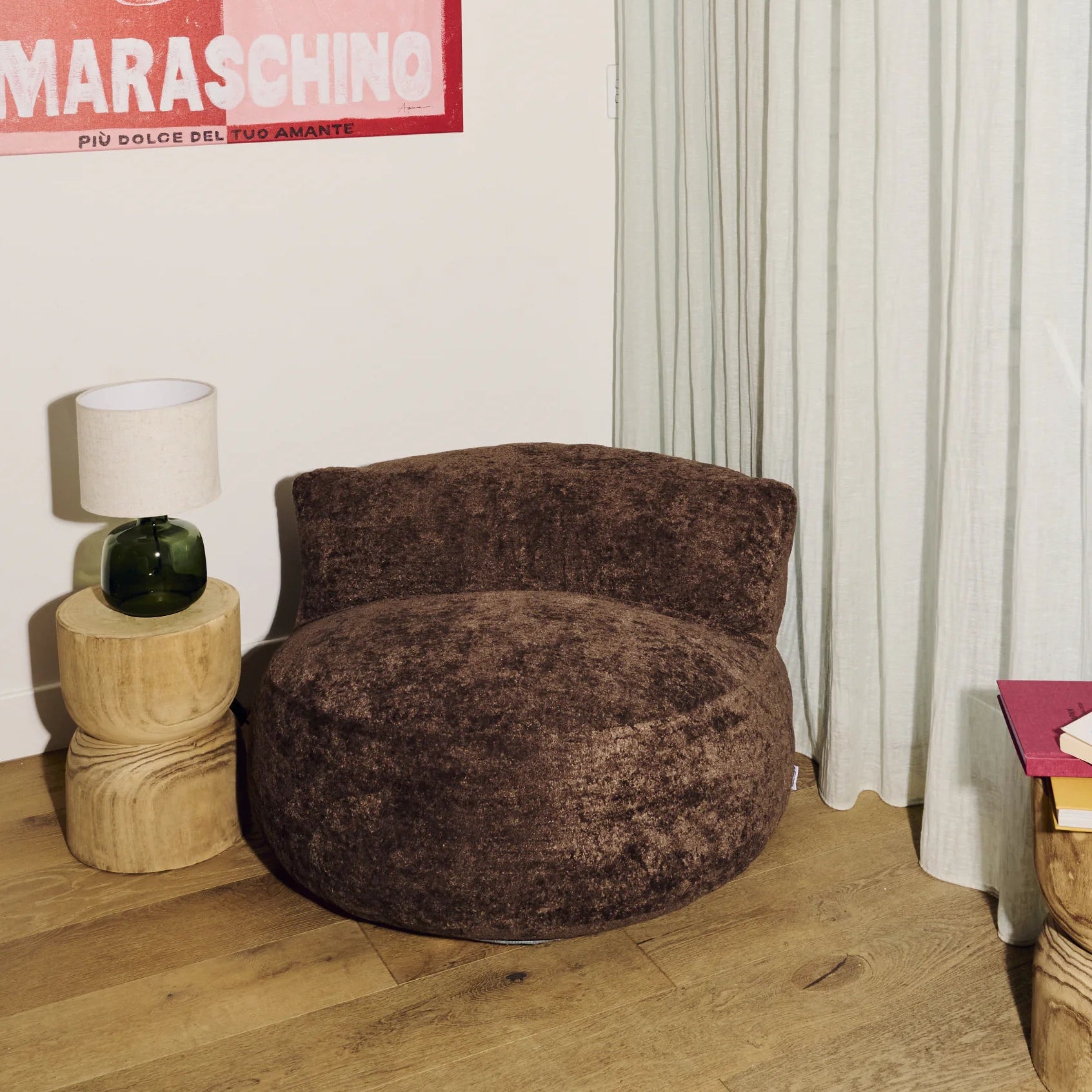 Brown plush chair in a room with a lamp and a poster on the wall.