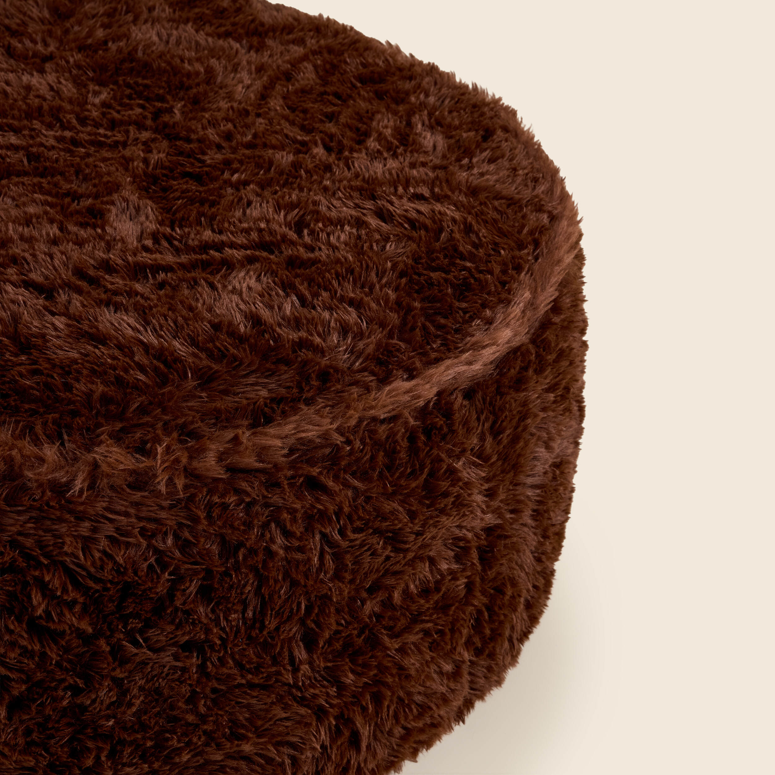 Close up of brown round ottoman on a beige background