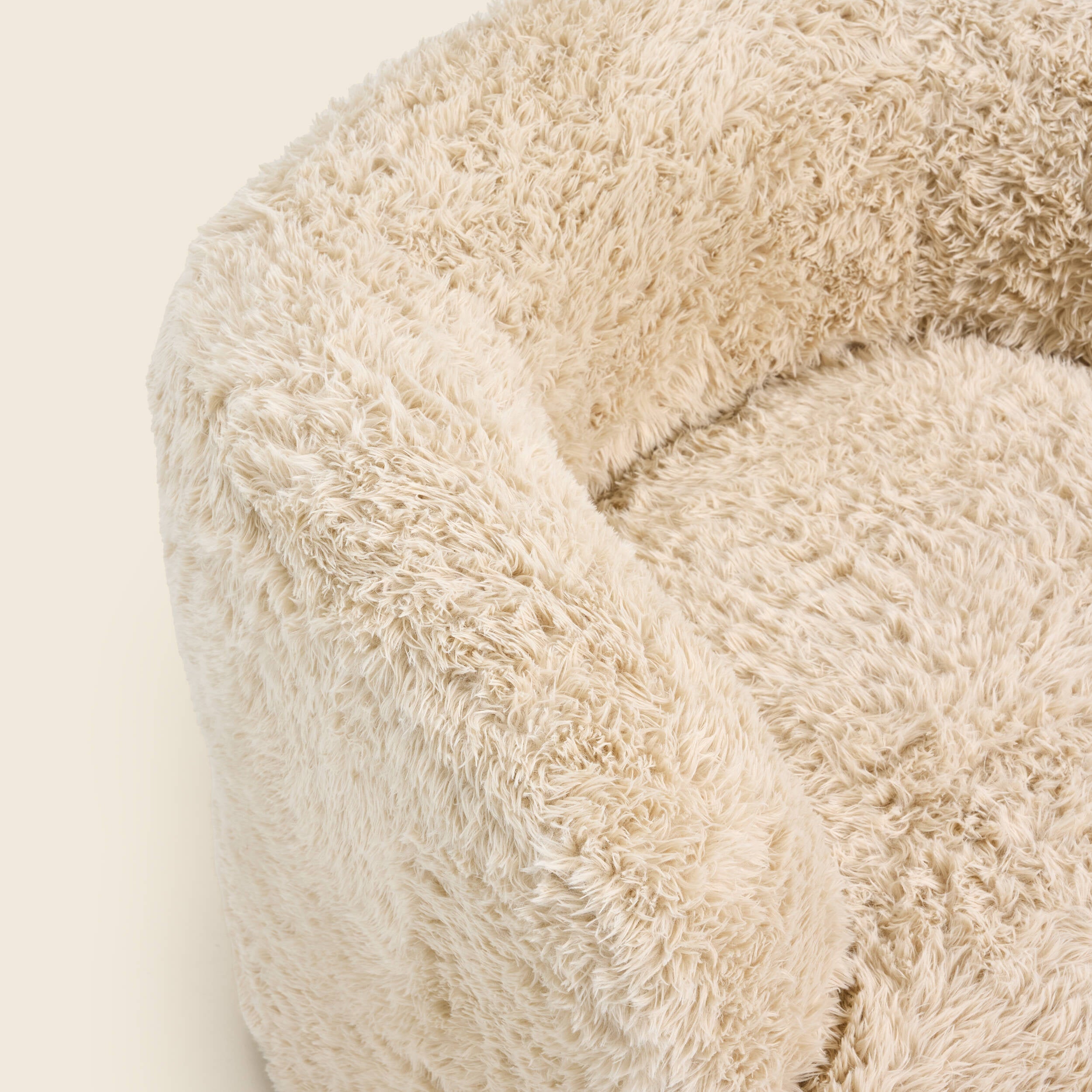 Close up of a beige fluffy armchair on a beige background