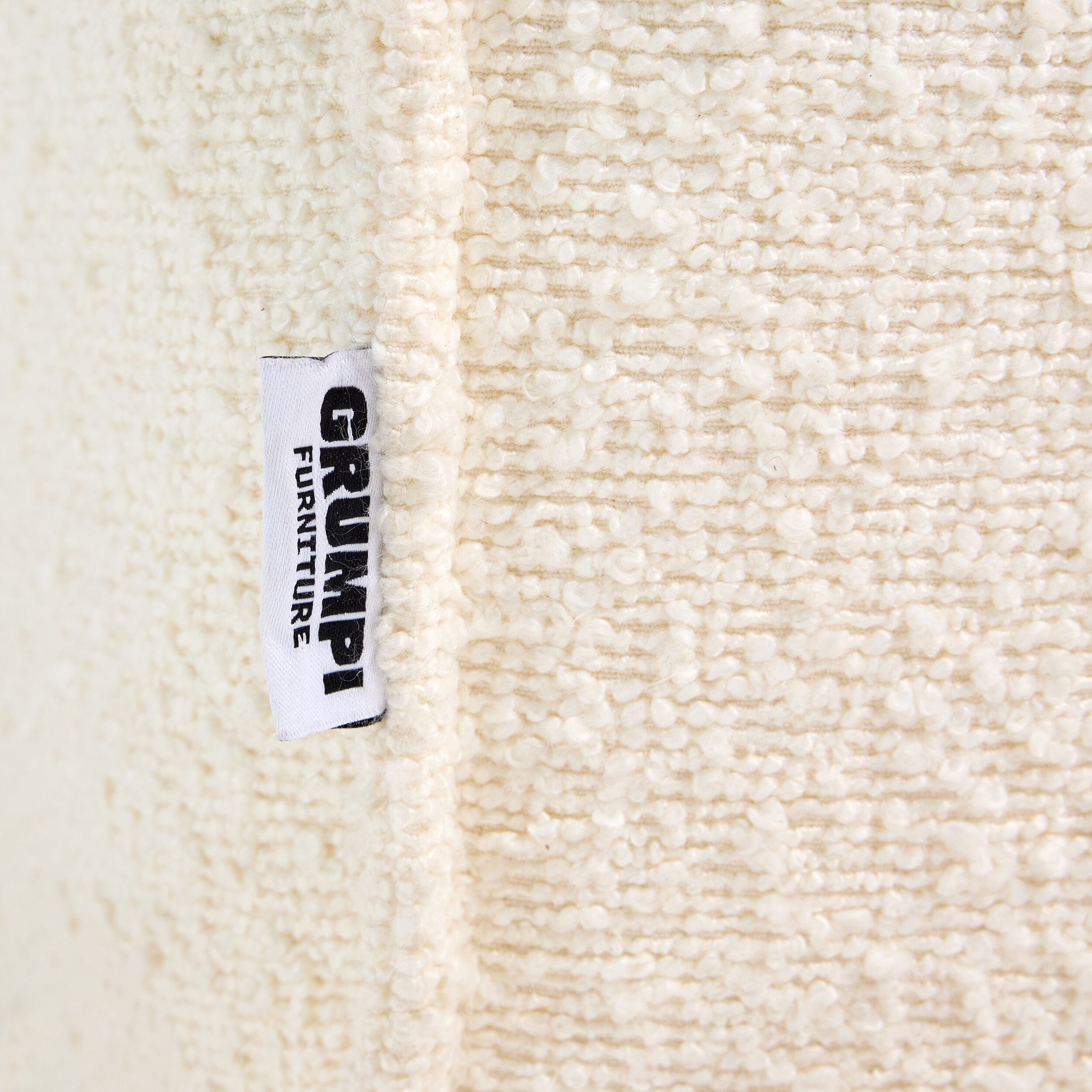 Ivory boucle Loungi modular chair detail on a beige background