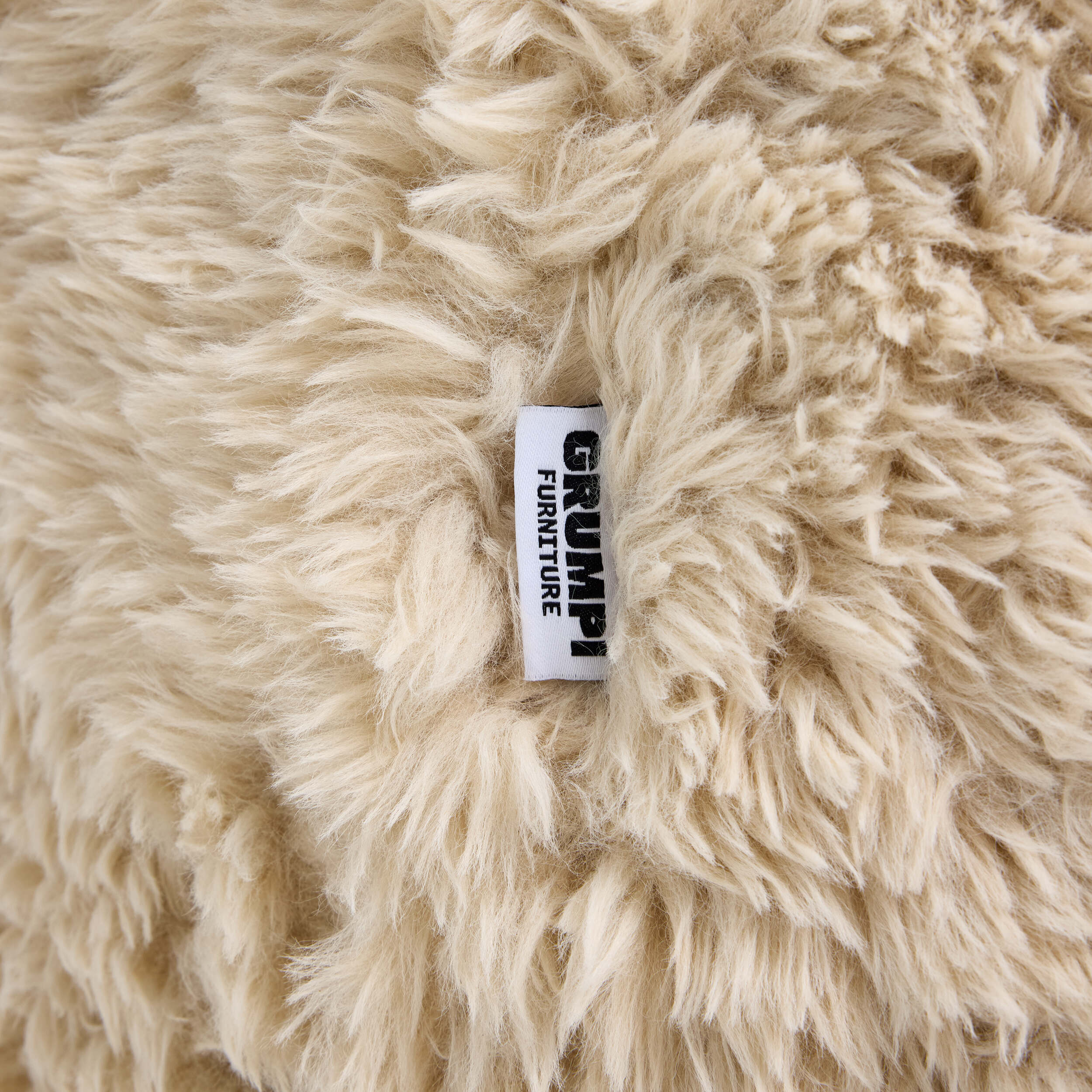 Beige fluffy fabric with a 'Grumpi Furniture' label