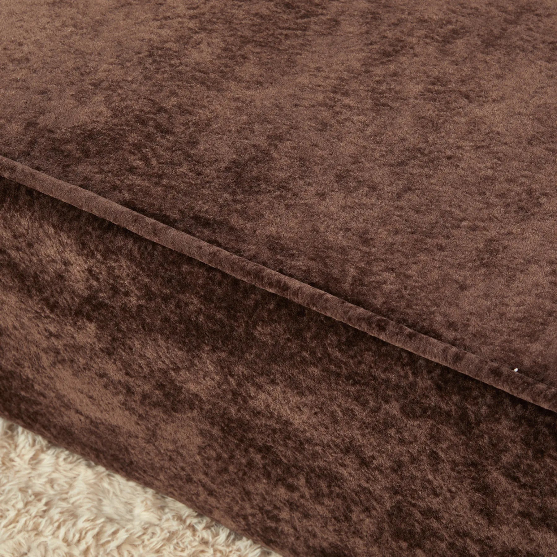 Close-up of brown textured fabric with a visible seam.