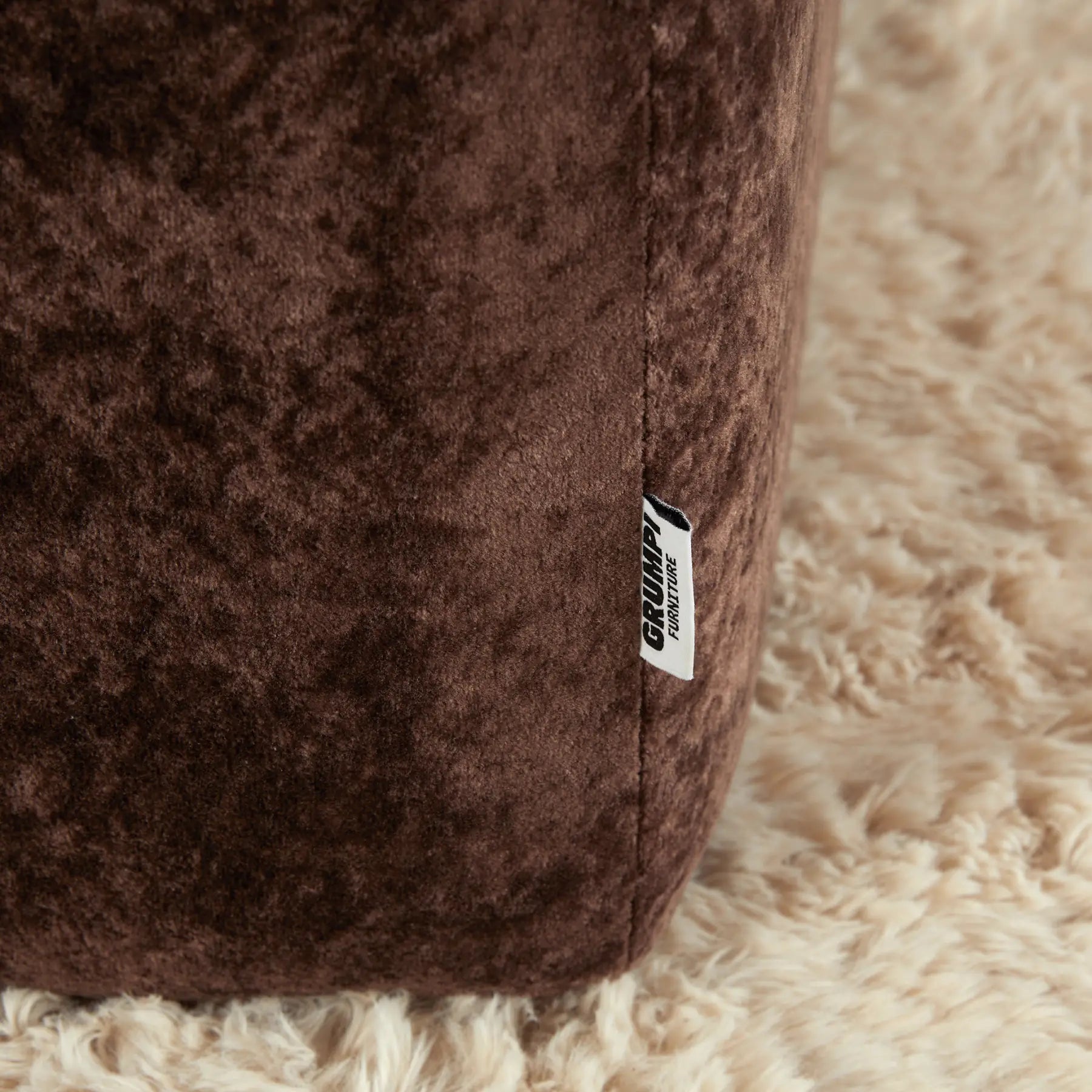 Brown plush toy with a 'Grumpy' label on a beige surface