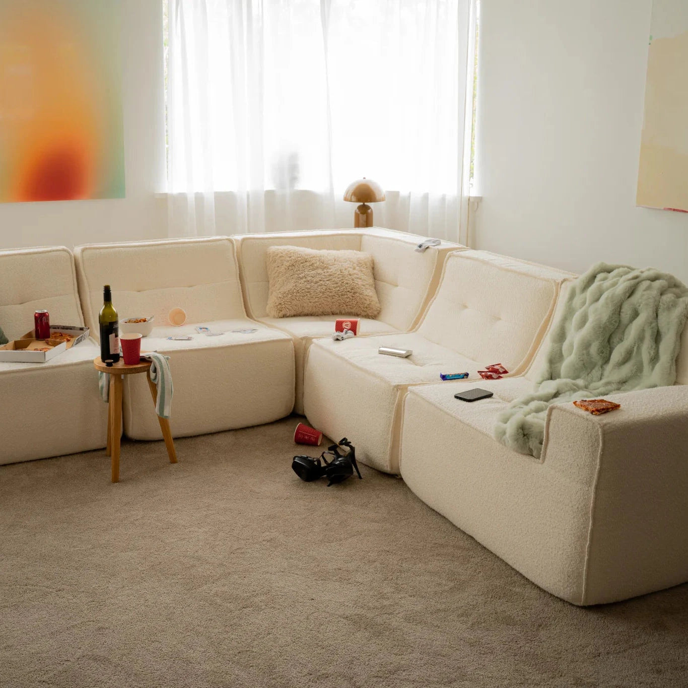 Beige sectional sofa in a living room with various items on it.