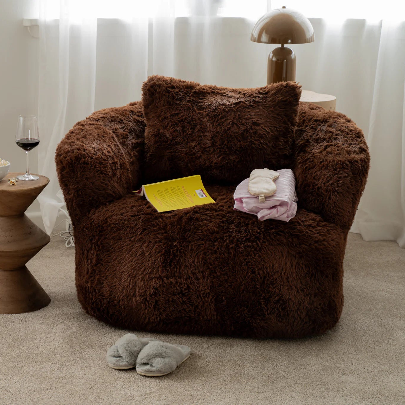 Brown fluffy armchair with a small table and slippers on a carpeted floor.