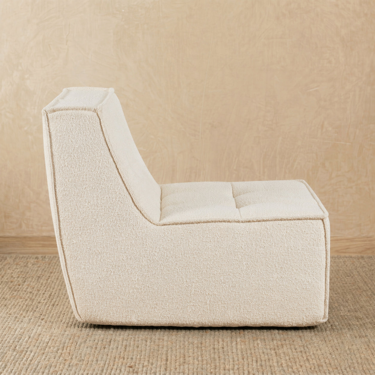 Beige armchair on a beige carpet with a beige wall background