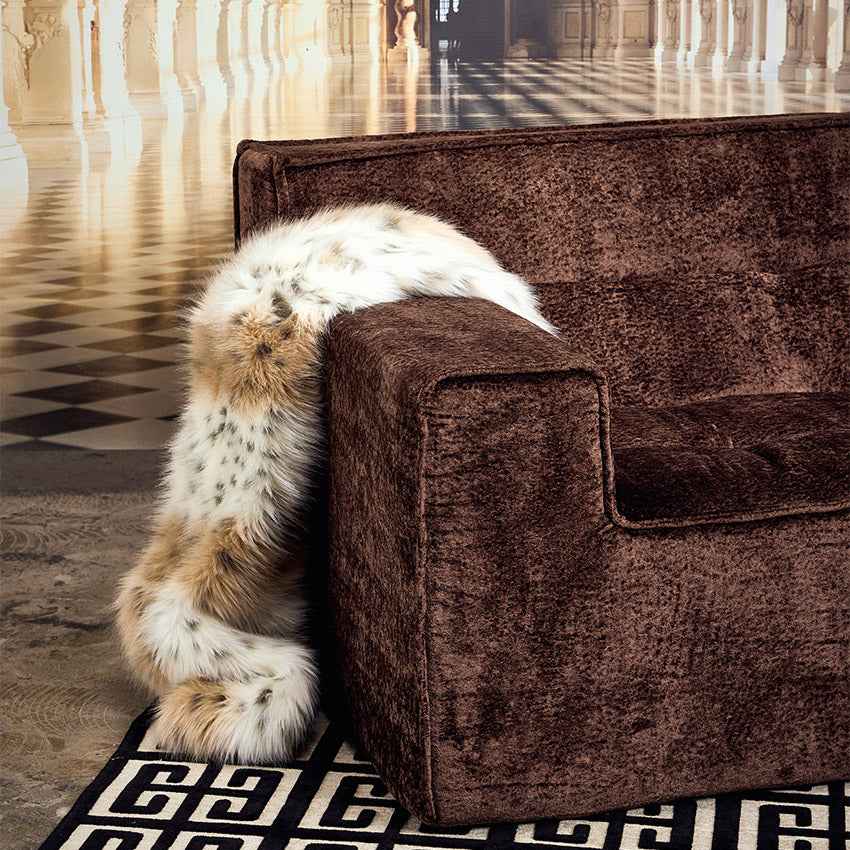 Brown textured right arm of a modular couch with fur thrown over