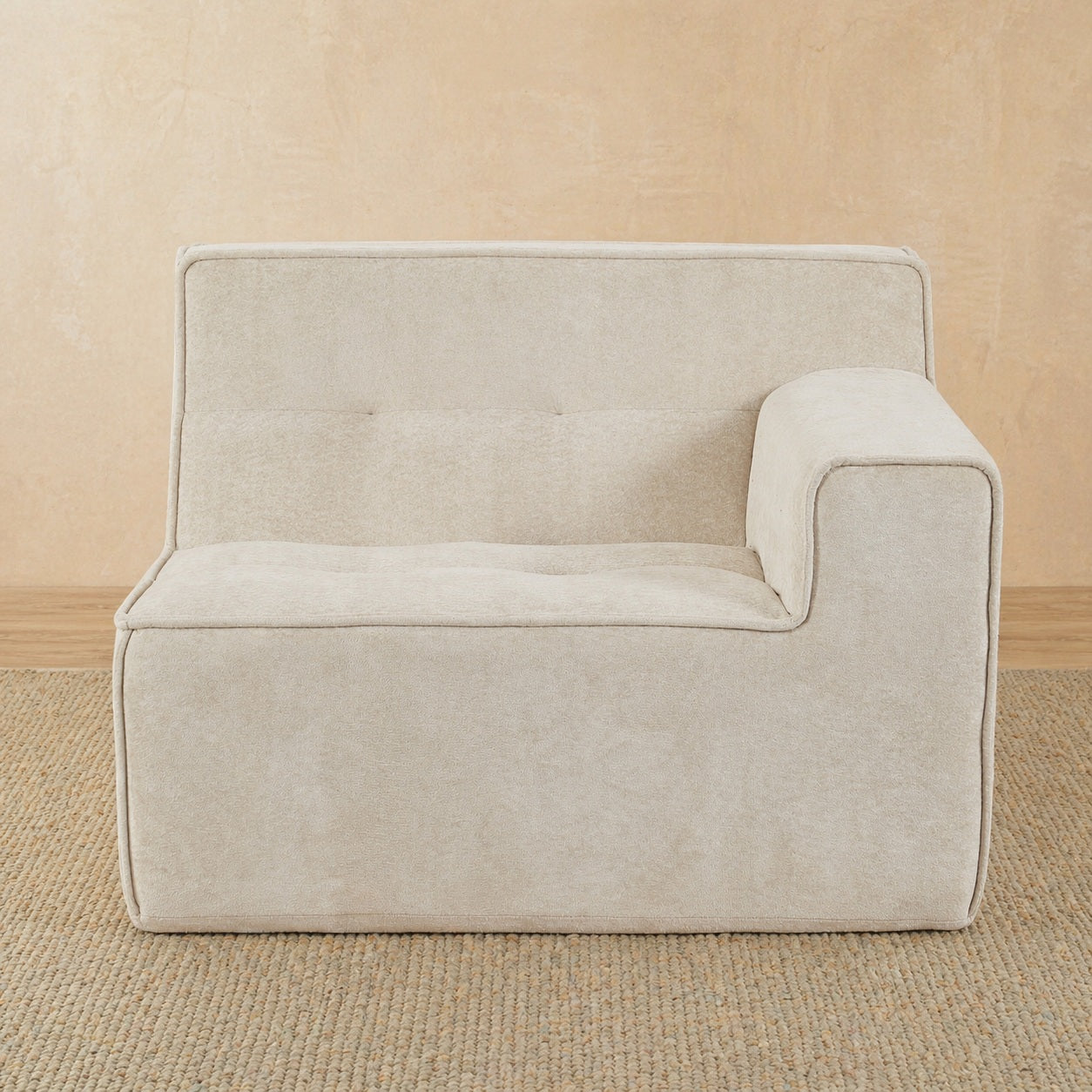 Beige armchair on a beige carpet with a neutral wall background