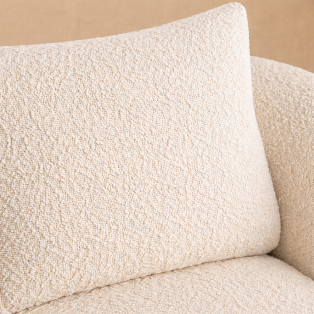 Close-up of a textured beige pillow on a matching sofa against a beige background