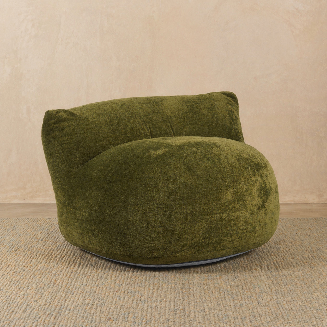 Green textured armchair on a beige carpet with a beige wall background