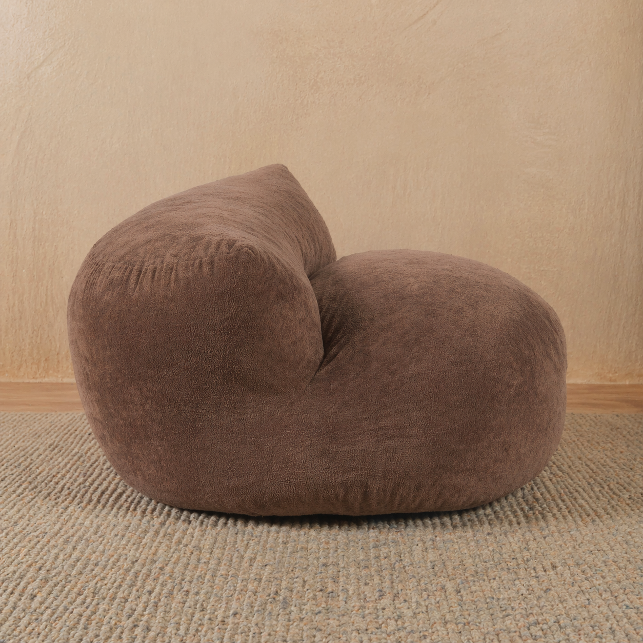 Brown bean bag chair on a beige carpet with a beige wall background