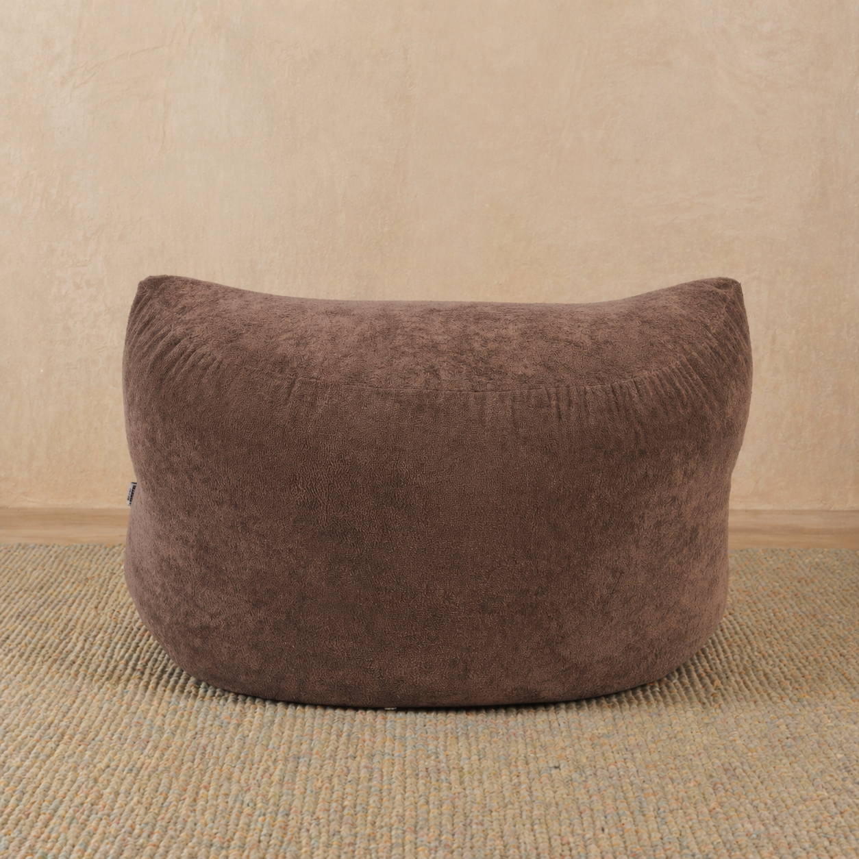 Brown bean bag chair on a beige carpet with a beige wall background