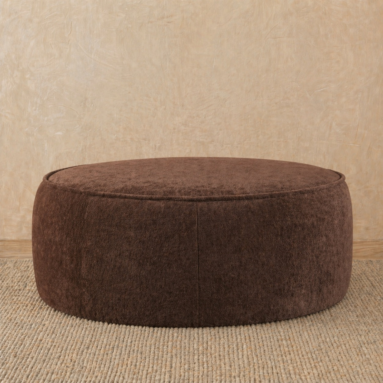 Brown ottoman on a beige carpet with a beige wall background