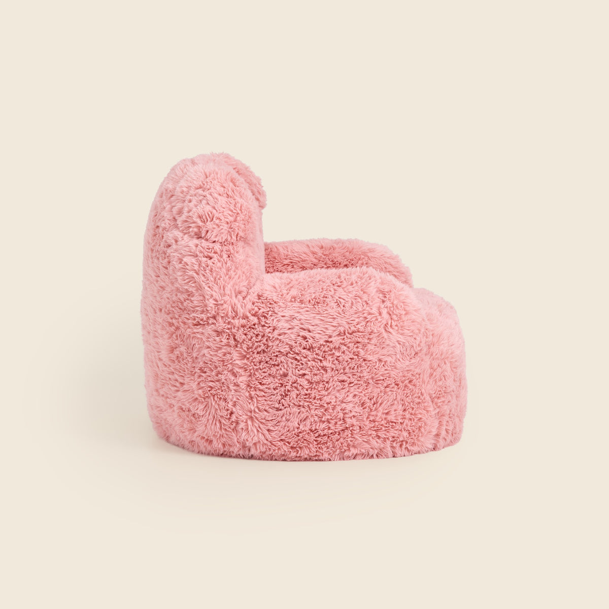 Side view of the pink Beari Kids Armchair on a beige background
