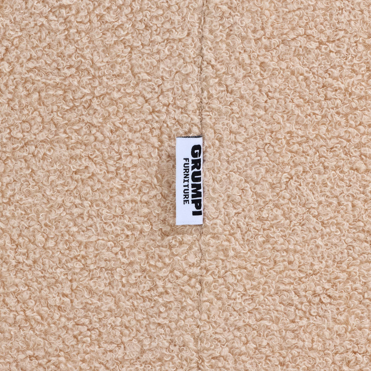 Close-up of the cream teddy fabric on the Teddi Kids Armchair, with the Grumpi Furniture label