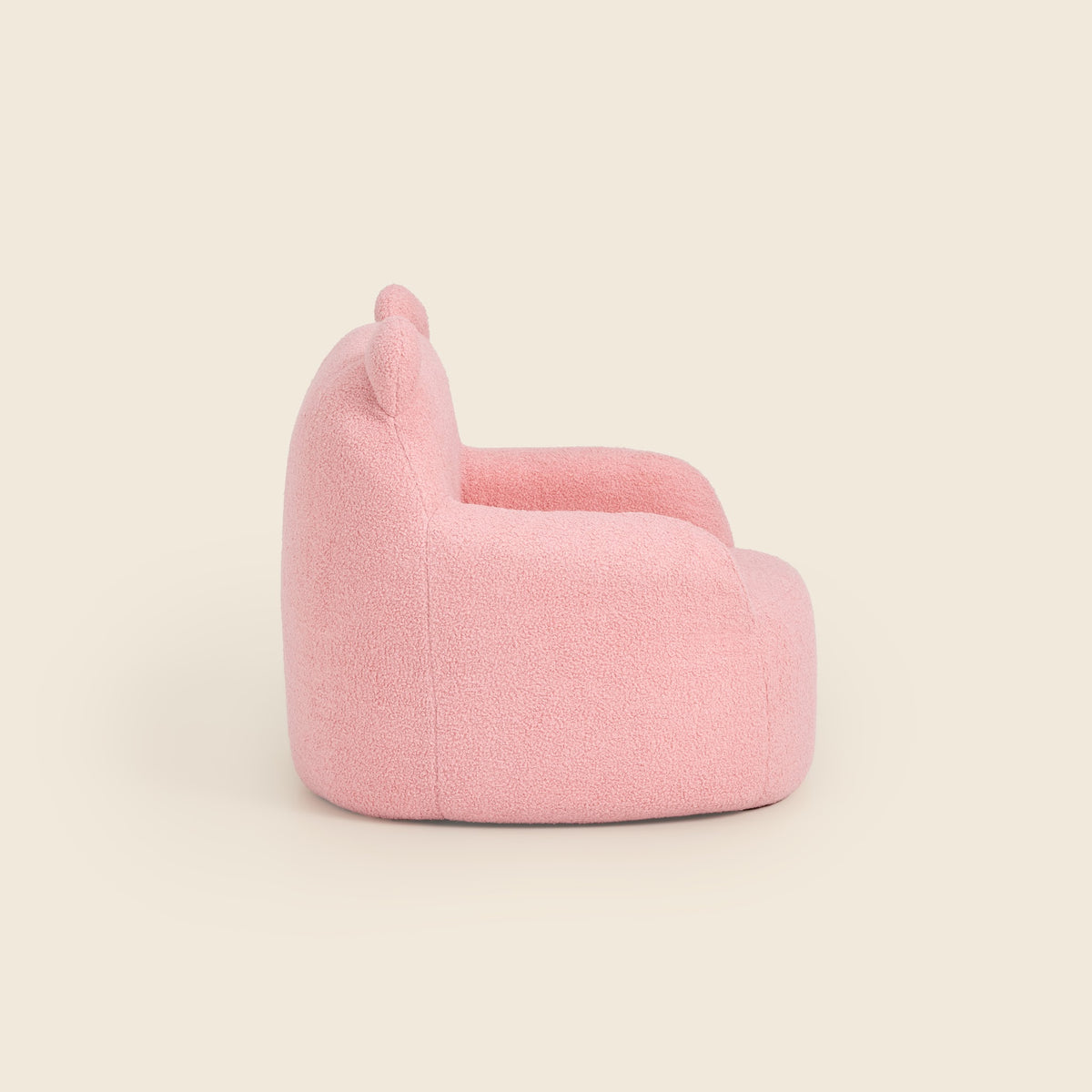 Side view of the pink Teddi Kids Armchair on a beige background