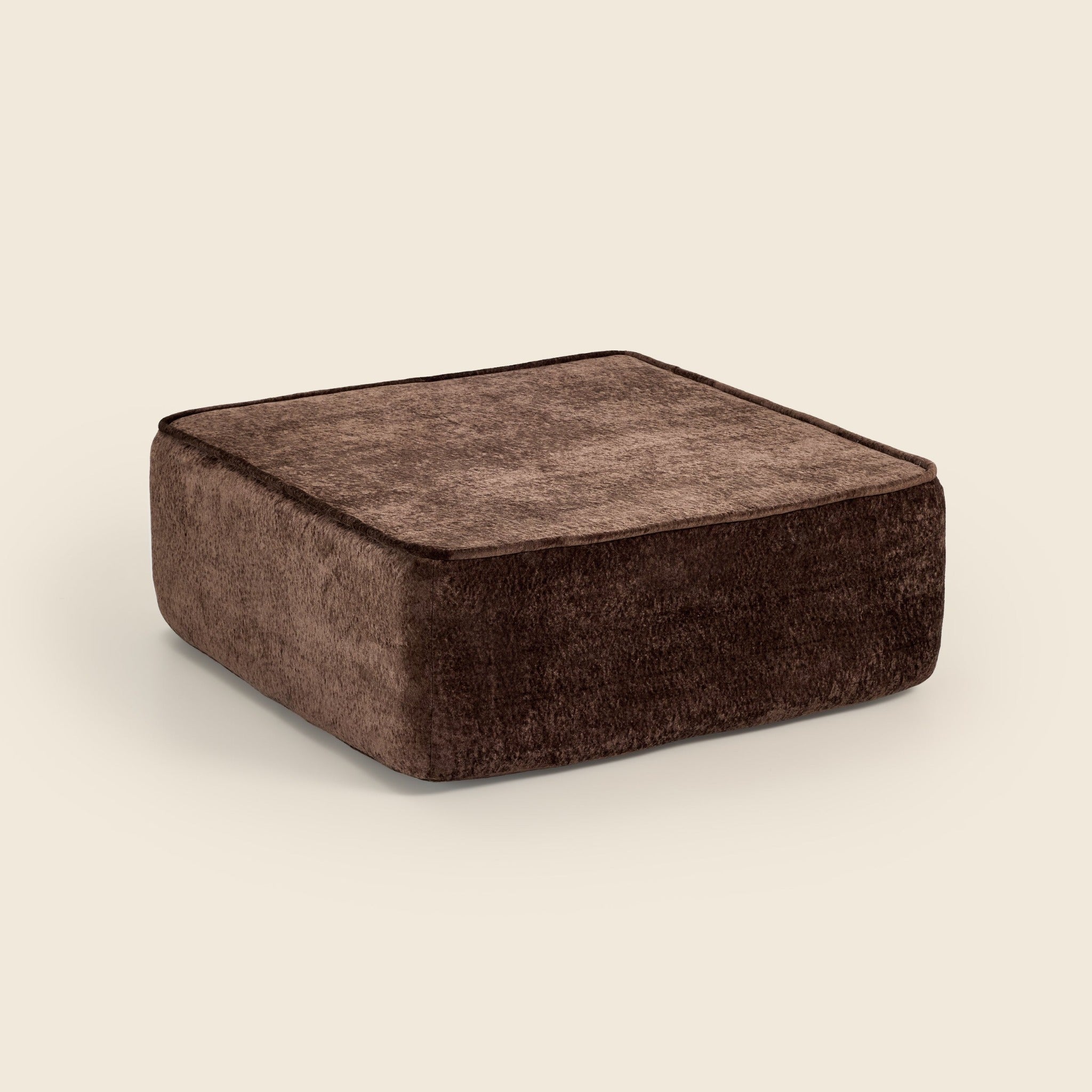 Brown textured square ottoman on a beige background. #color_brown-snow-velvet