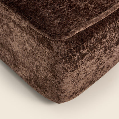 Close-up of a brown textured ottoman corner on a light beige background

