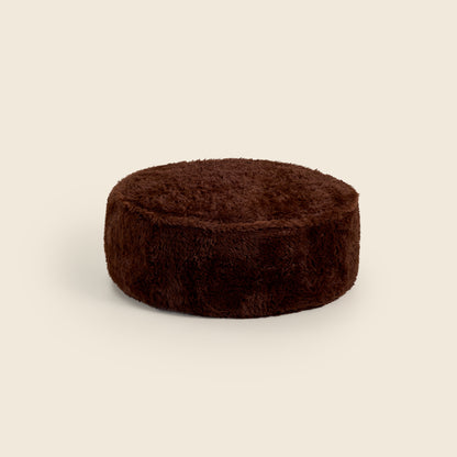 Brown round ottoman on a beige background
