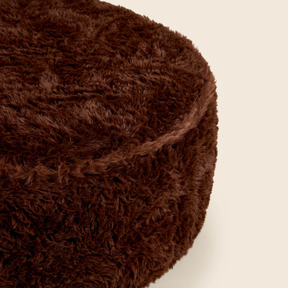Close up of brown round ottoman on a beige background
