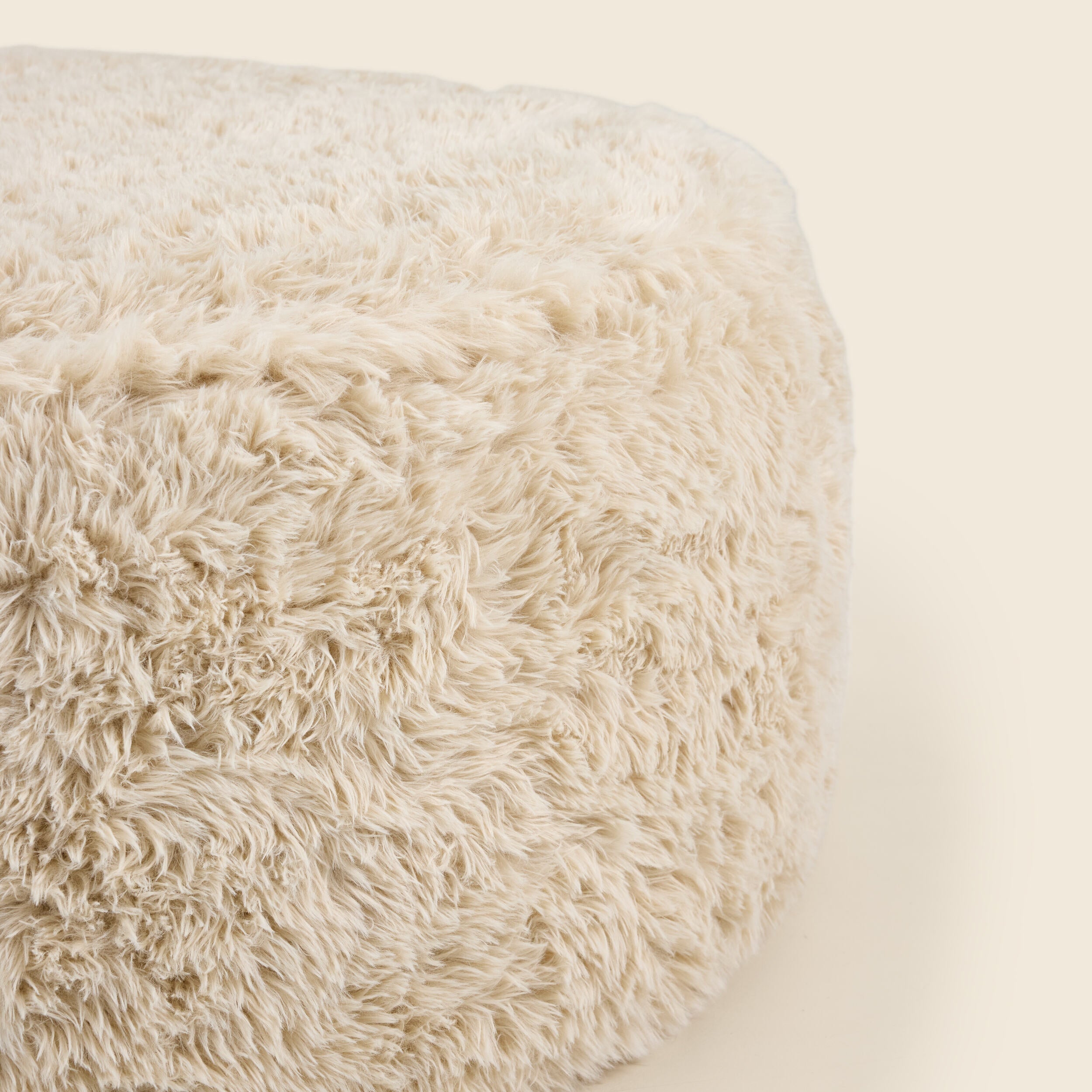 Close up of round beige pouf on a beige background
