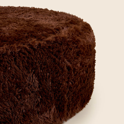 Close up of brown round ottoman on a beige background
