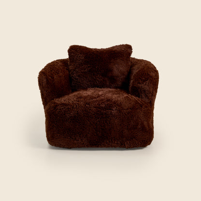 Brown plush armchair with a pillow on a beige background 

