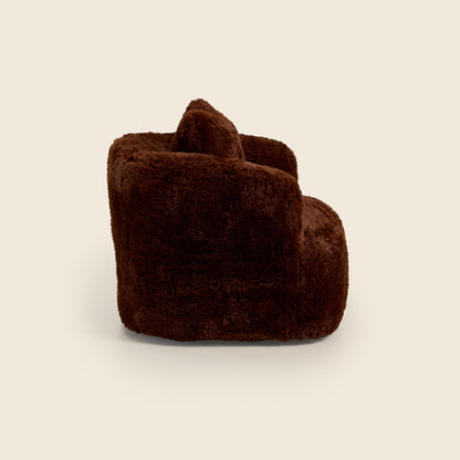 Brown plush armchair on a beige background 

