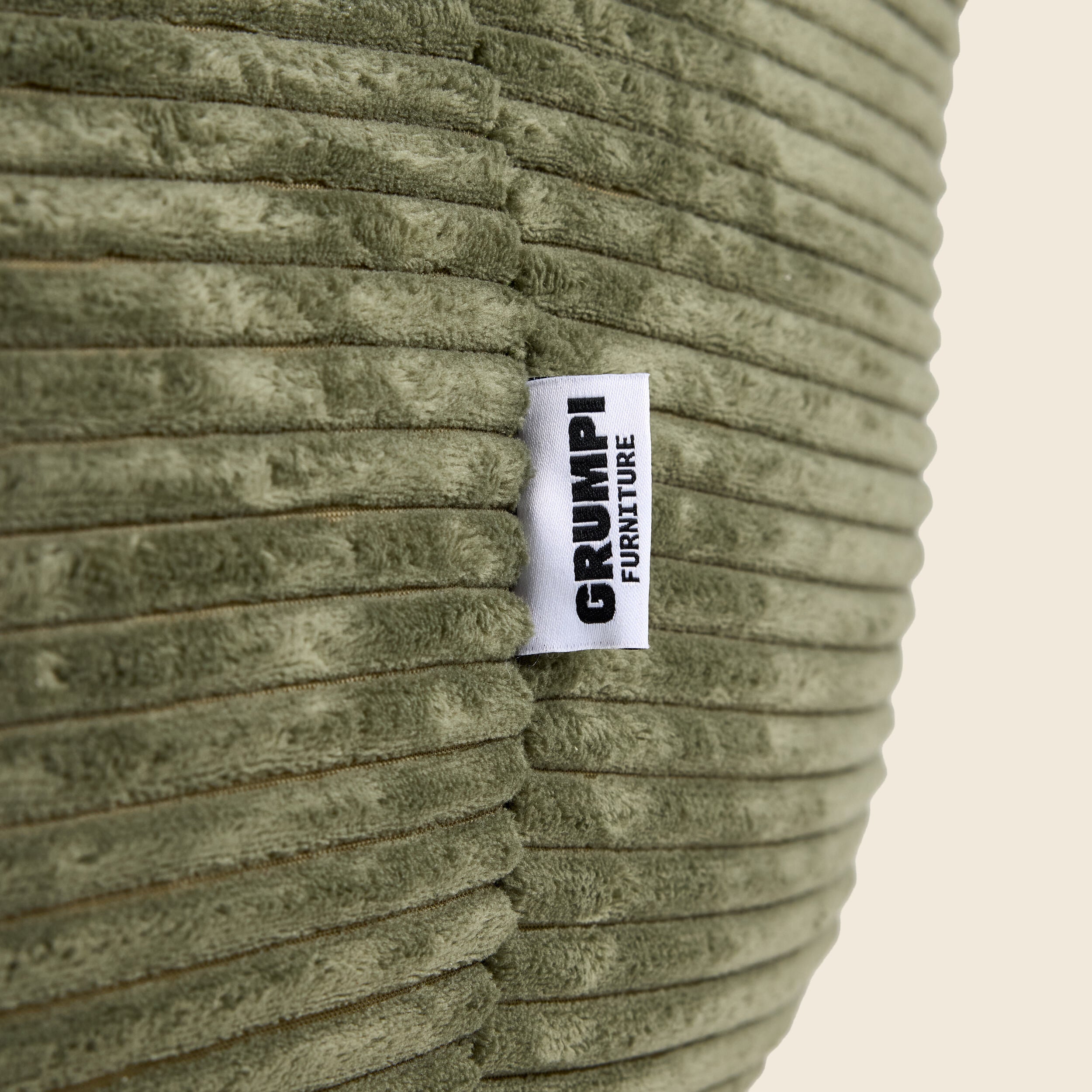 Textured green fabric with a 'Grumpi Furniture' label on a beige background
