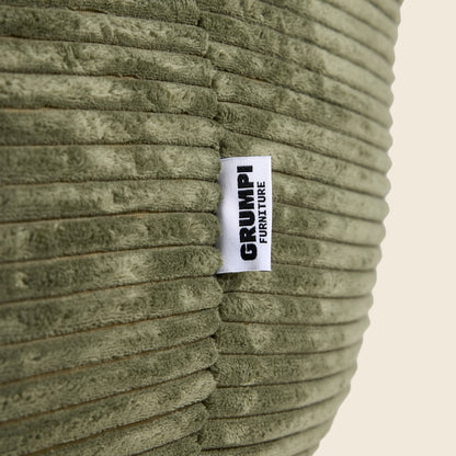 Textured green fabric with a 'Grumpi Furniture' label on a beige background
