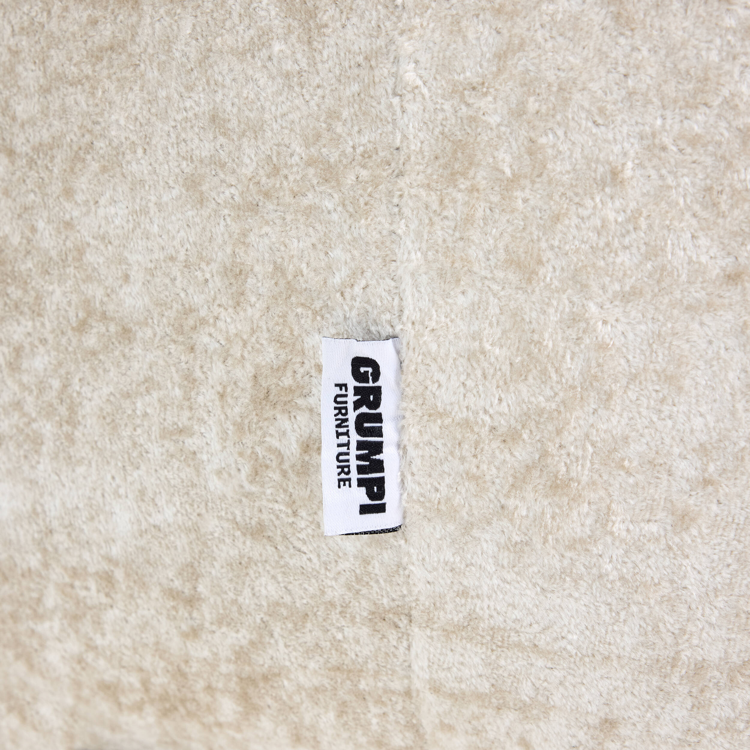 Textile label with 'GRUMP' on a beige fabric background
