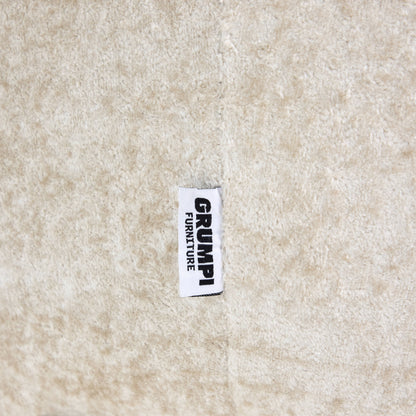 Textile label with 'GRUMP' on a beige fabric background
