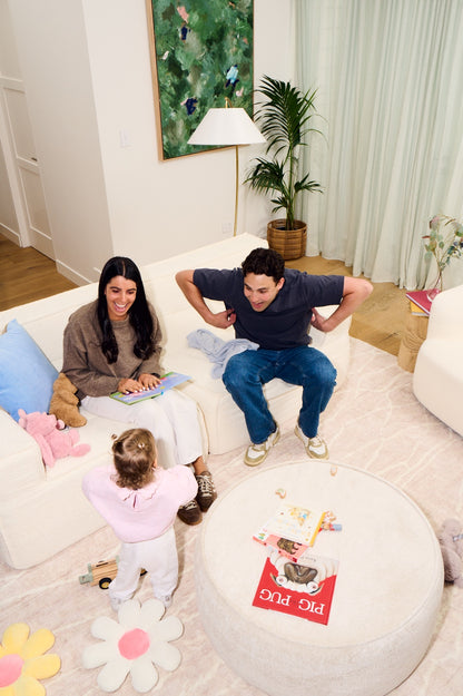 Family reading books together on a couch in a cozy living room. 
