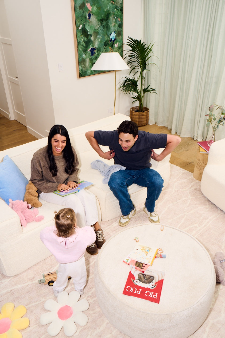 Family reading books together on a couch in a cozy living room. 