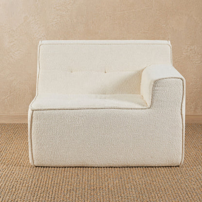 Beige armchair against a beige wall on a textured brown floor 