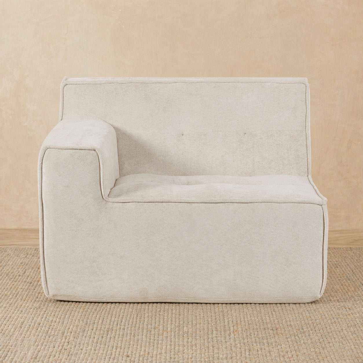 Beige armchair on a beige carpet with a beige wall background 