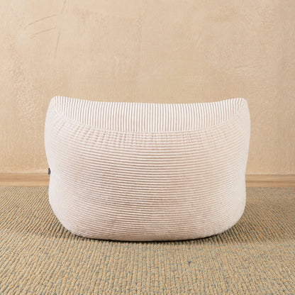 Beige textured ottoman on a beige carpet with a beige wall background 