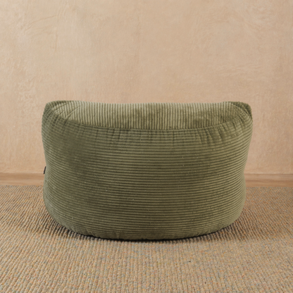 Green textured ottoman on a beige floor with a beige wall background 