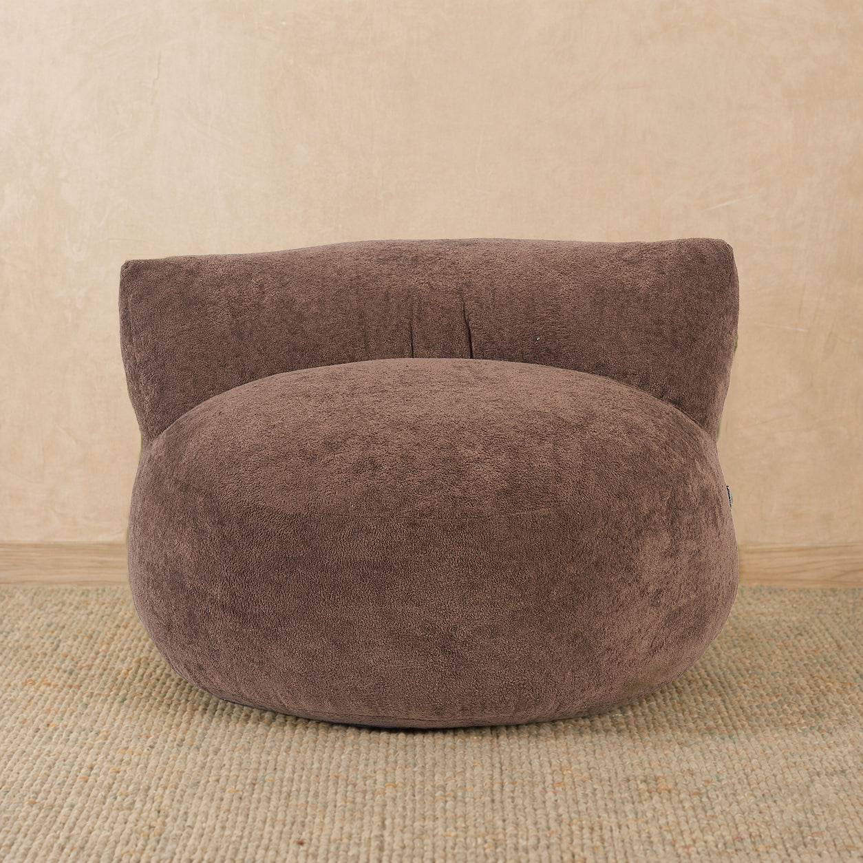 Brown bean bag chair on a beige carpet with a beige wall background 