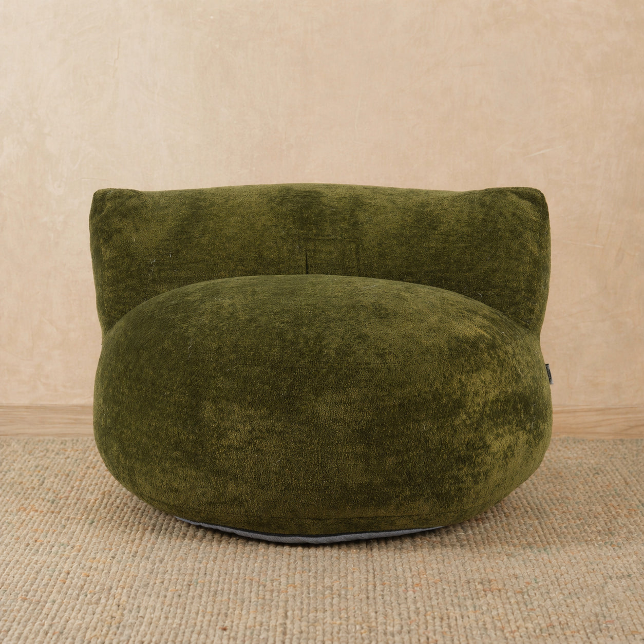 Green bean bag chair on a beige carpet with a beige wall background 