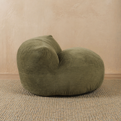 Green corduroy armchair on a beige carpet with a beige wall background 