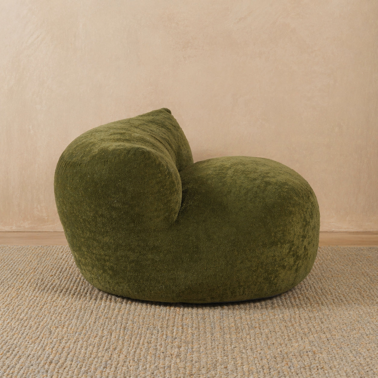Green bean bag chair on a beige carpet with a beige wall background 