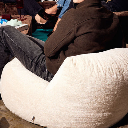 Back of a White bean bag chair with a  male sitting on it 