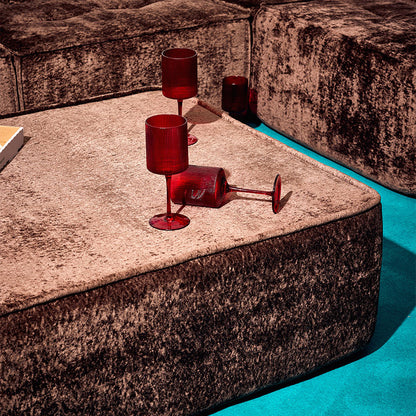 Brown textured ottoman on a a blue rug with red cups
