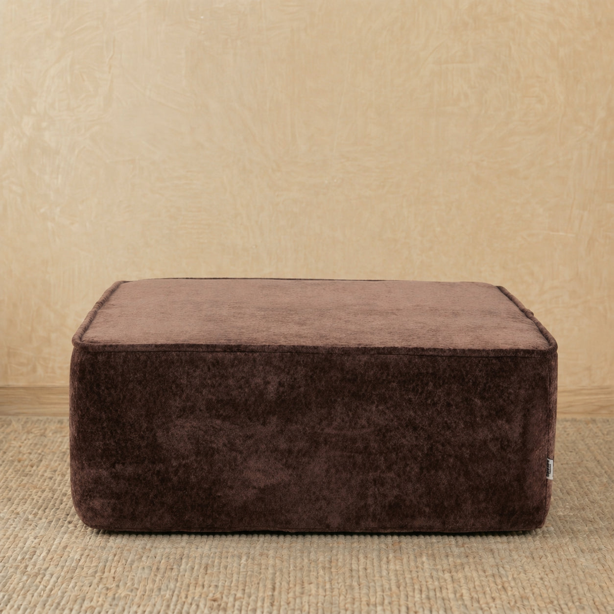 Brown ottoman on a beige carpet with a beige wall background 