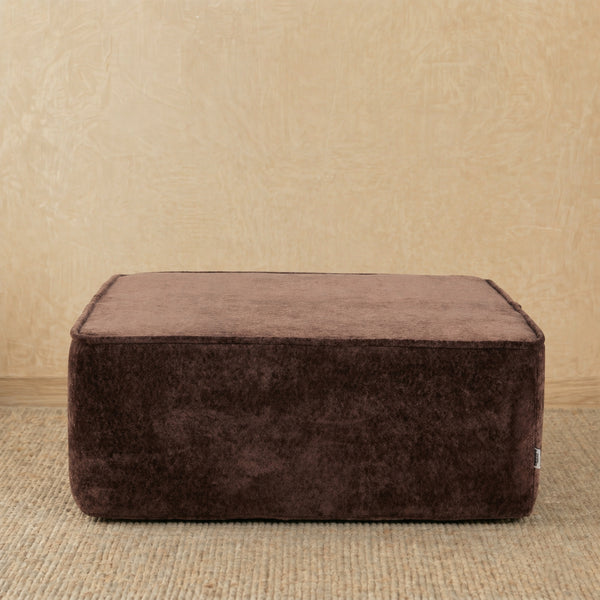 Brown ottoman on a beige carpet with a beige wall background #color_brown-snow-velvet