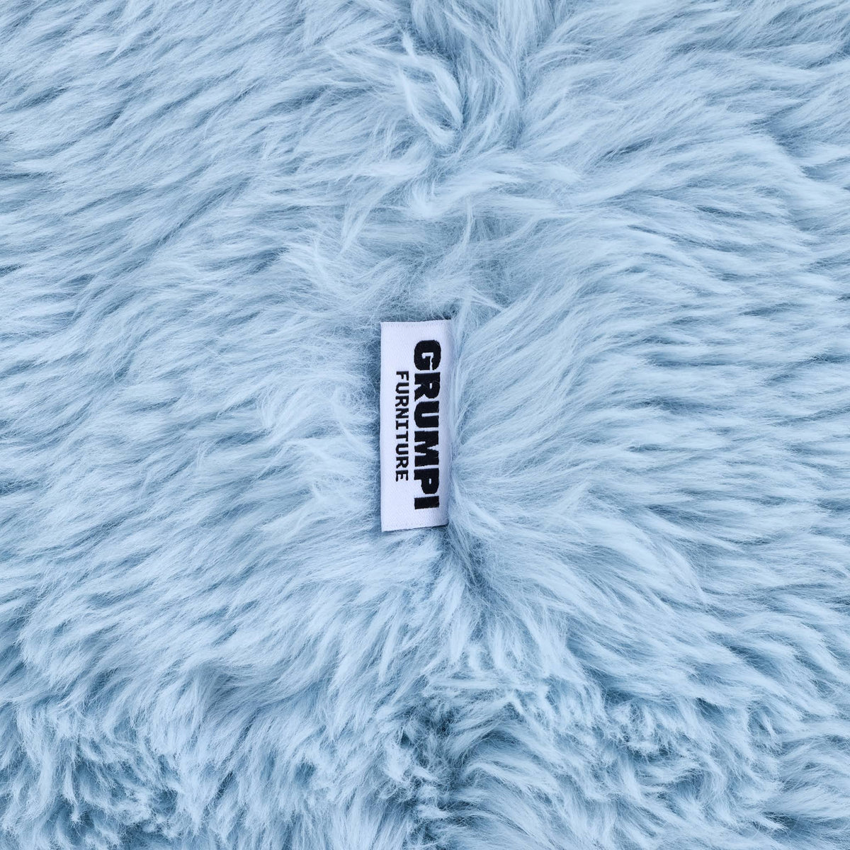 Close-up of the blue faux fur on the Beari Kids Armchair, with the Grumpi Furniture label 