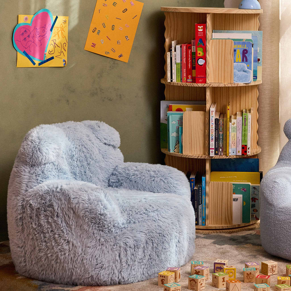 Blue Beari Kids Armchair in a reading nook beside a bookshelf and wooden toy blocks 