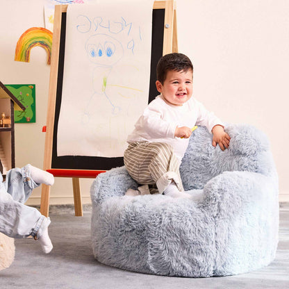 Toddler climbing into the blue Beari Kids Armchair beside an easel 