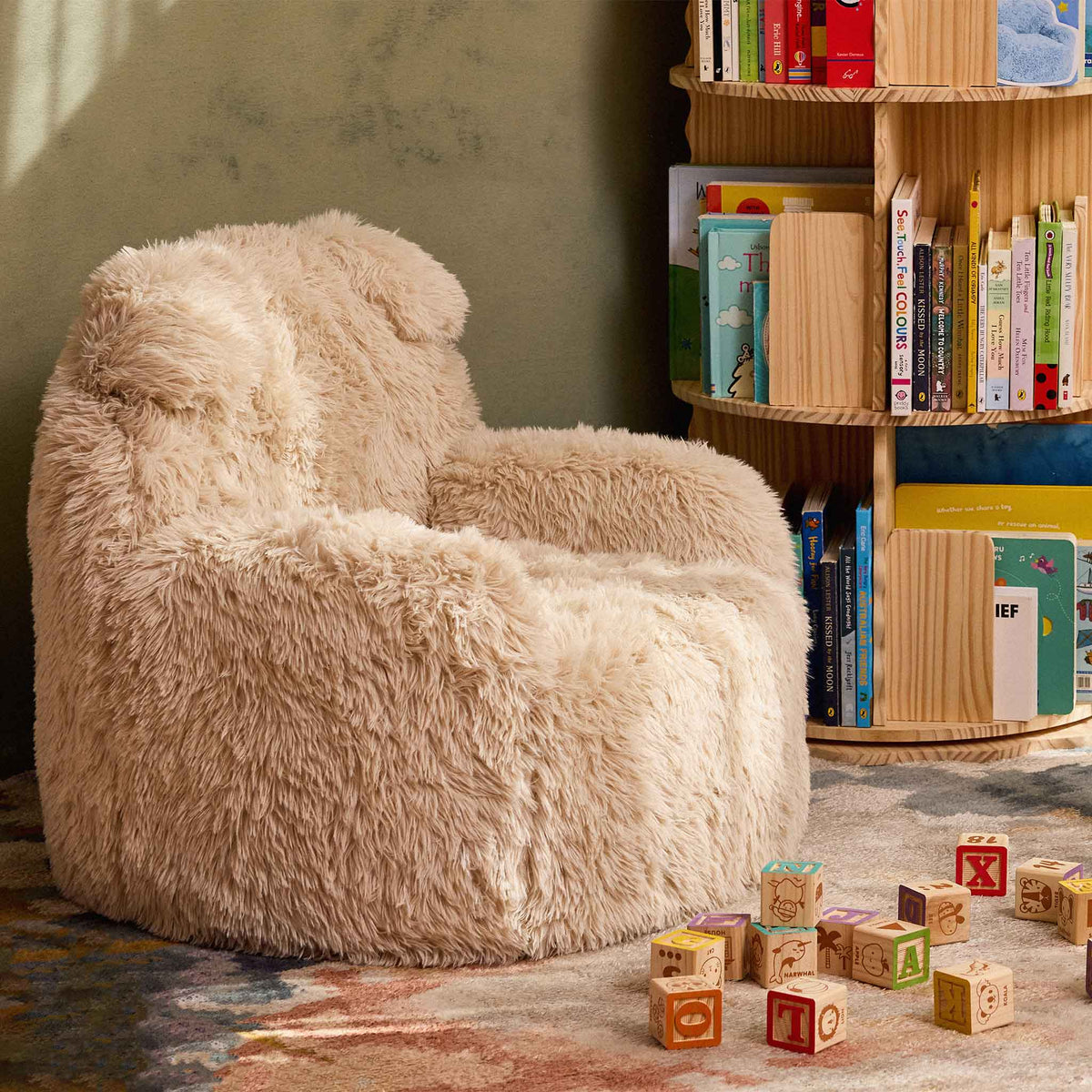 Cream Beari Kids Armchair in a reading nook beside a bookshelf and wooden toy blocks 